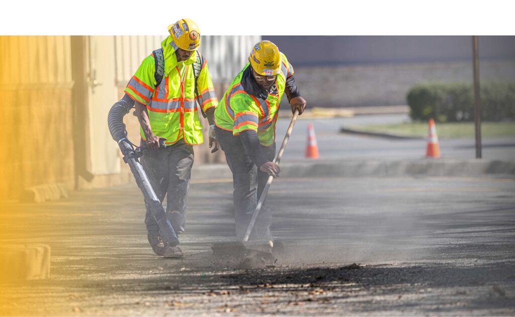 Workers in vests cleaning asphalt