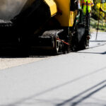 Worker in vest with shovel paving road