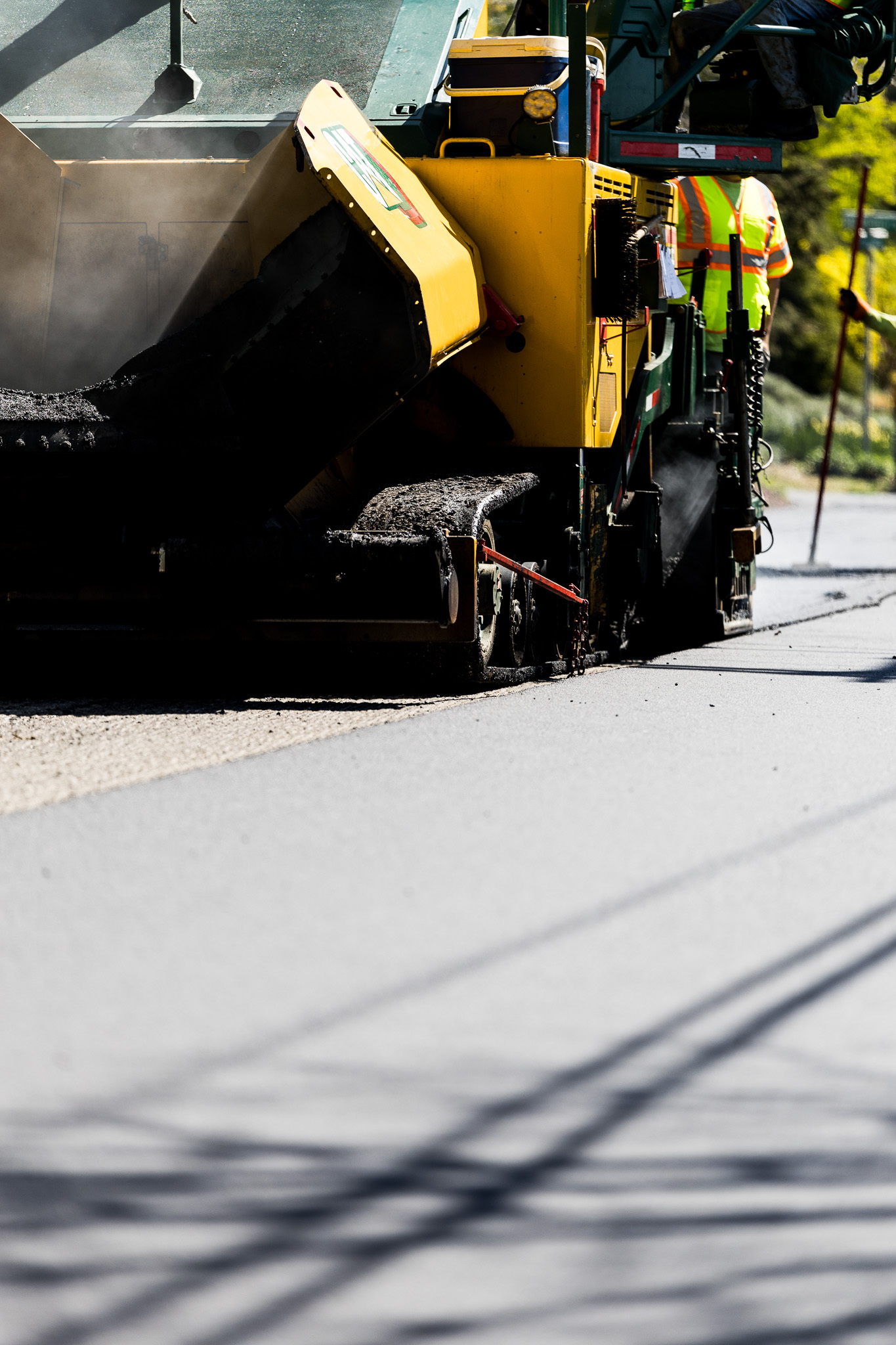 Worker in vest with shovel paving road