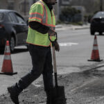 Vehicle and worker with vest paving surface