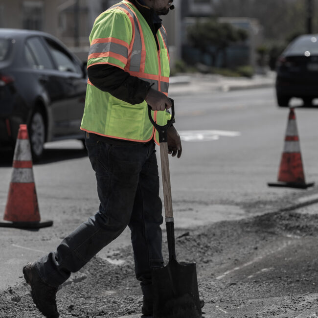 Vehicle and worker with vest paving surface