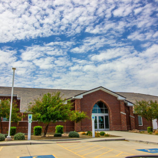 Brick church with steeple with view of parking lot