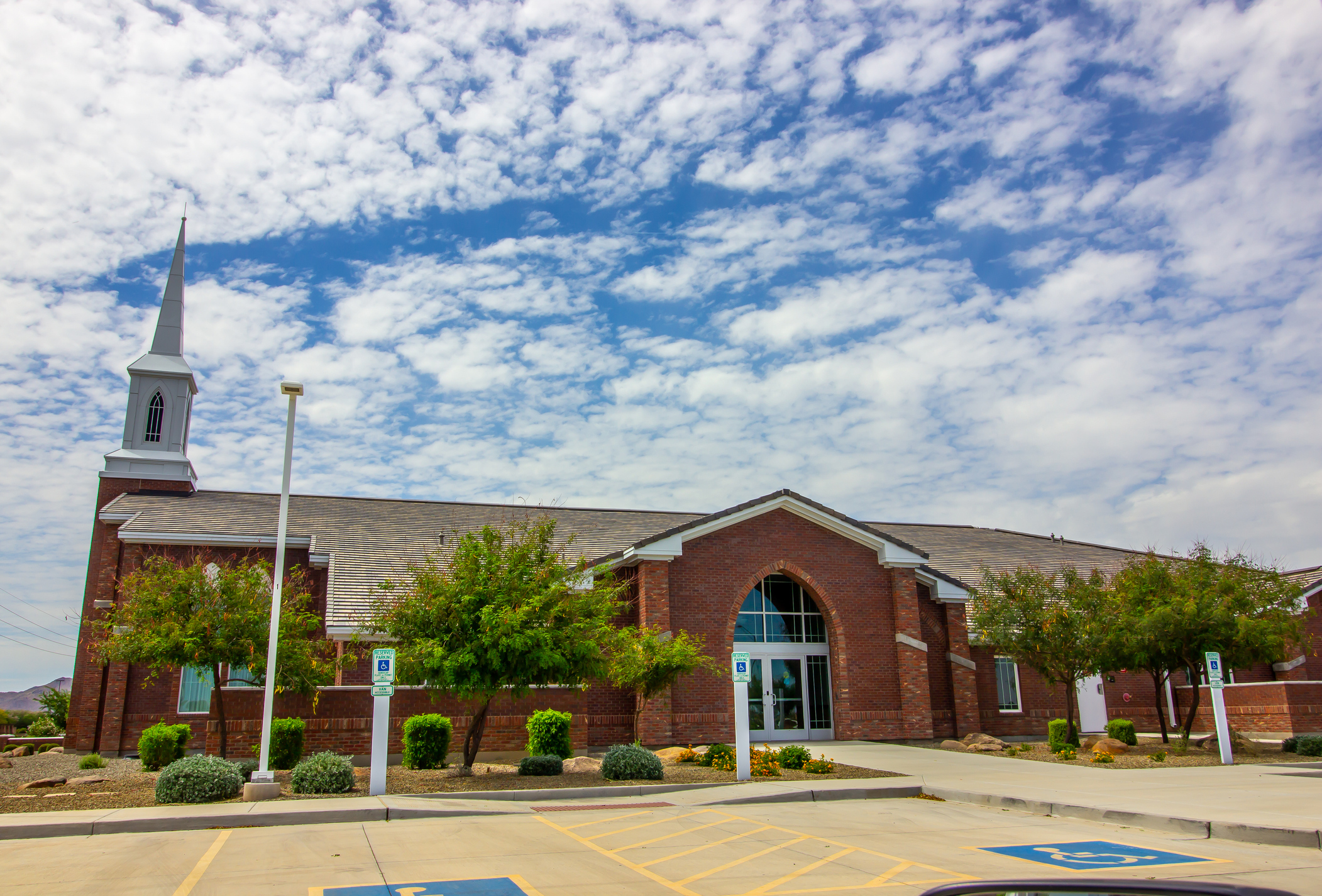 Brick church with steeple with view of parking lot