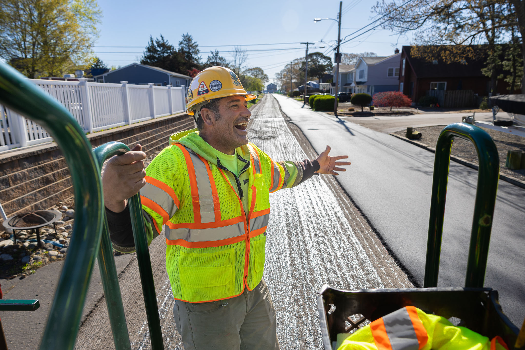 Construction contractor wearing gear and working on stripping road with tool and riding on back of truck