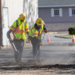 Construction workers stripping asphalt back from commercial parking lot