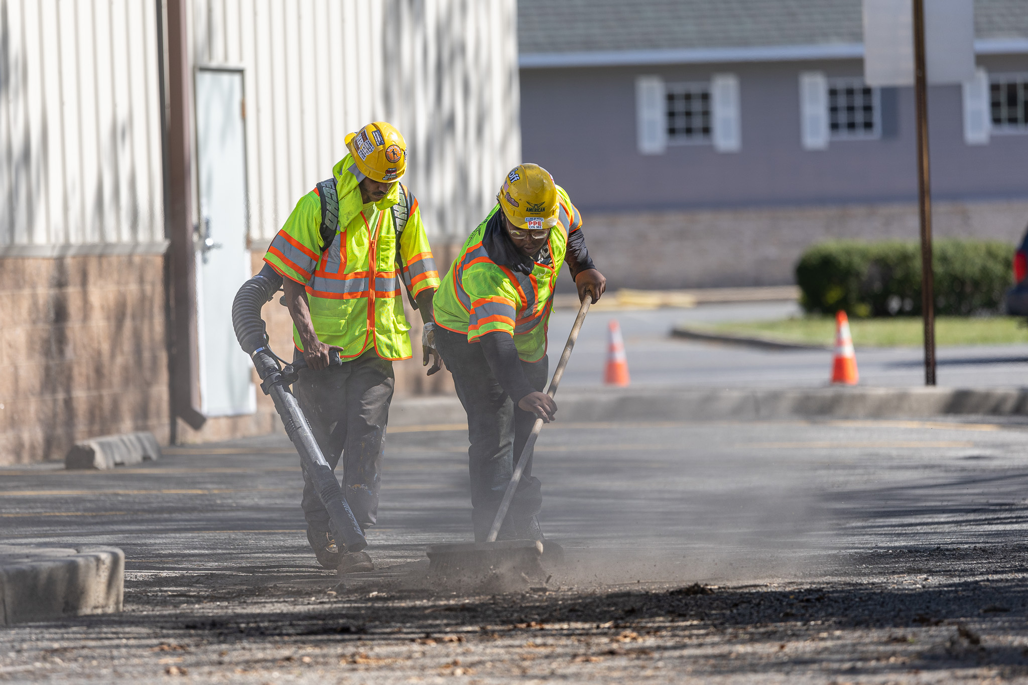 Construction workers stripping asphalt back from commercial parking lot