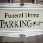 Finger pointing on sign to funeral home parking lot