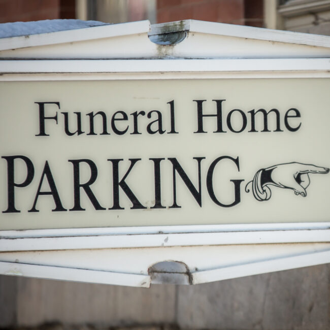 Finger pointing on sign to funeral home parking lot