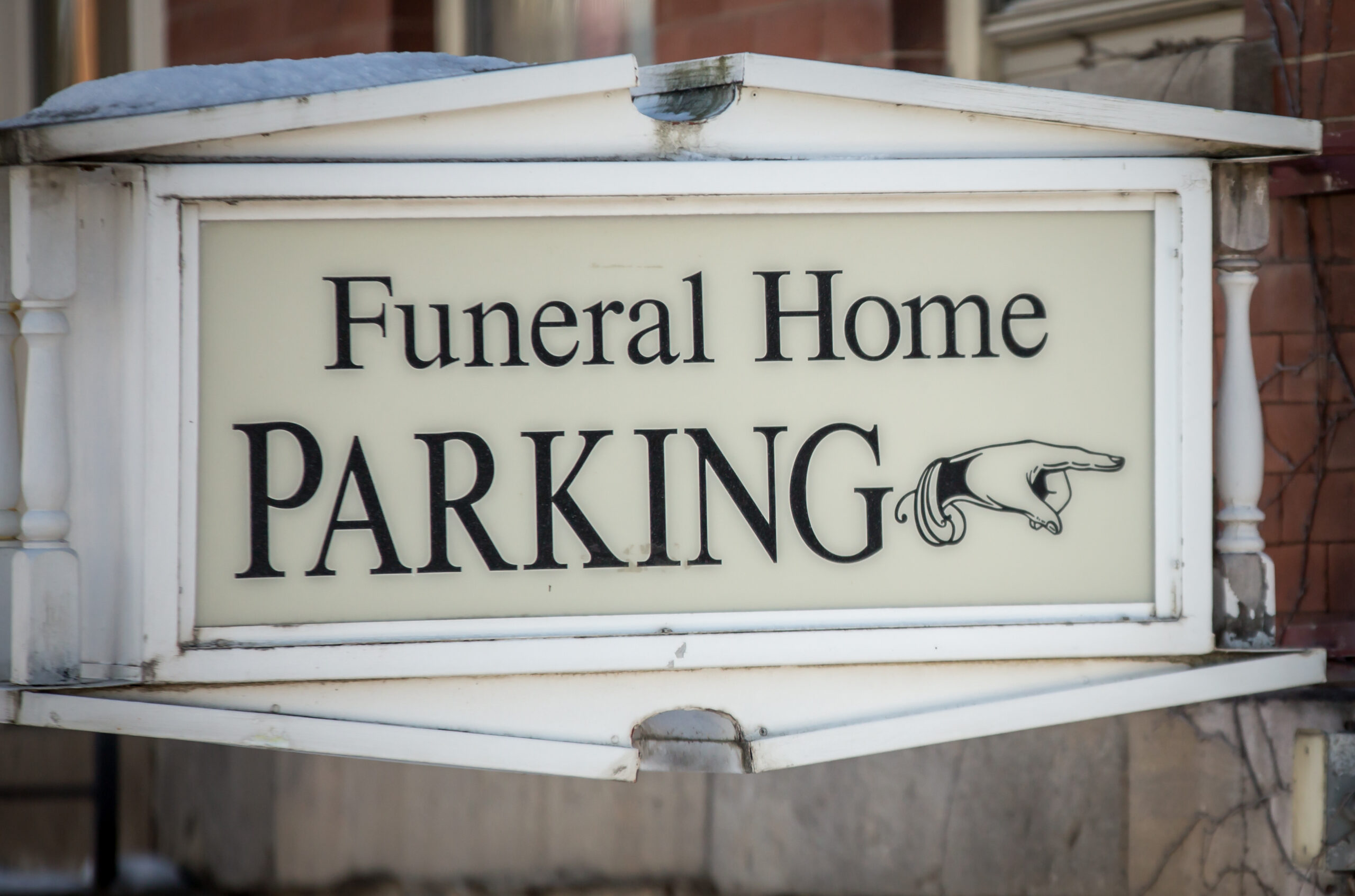 Finger pointing on sign to funeral home parking lot