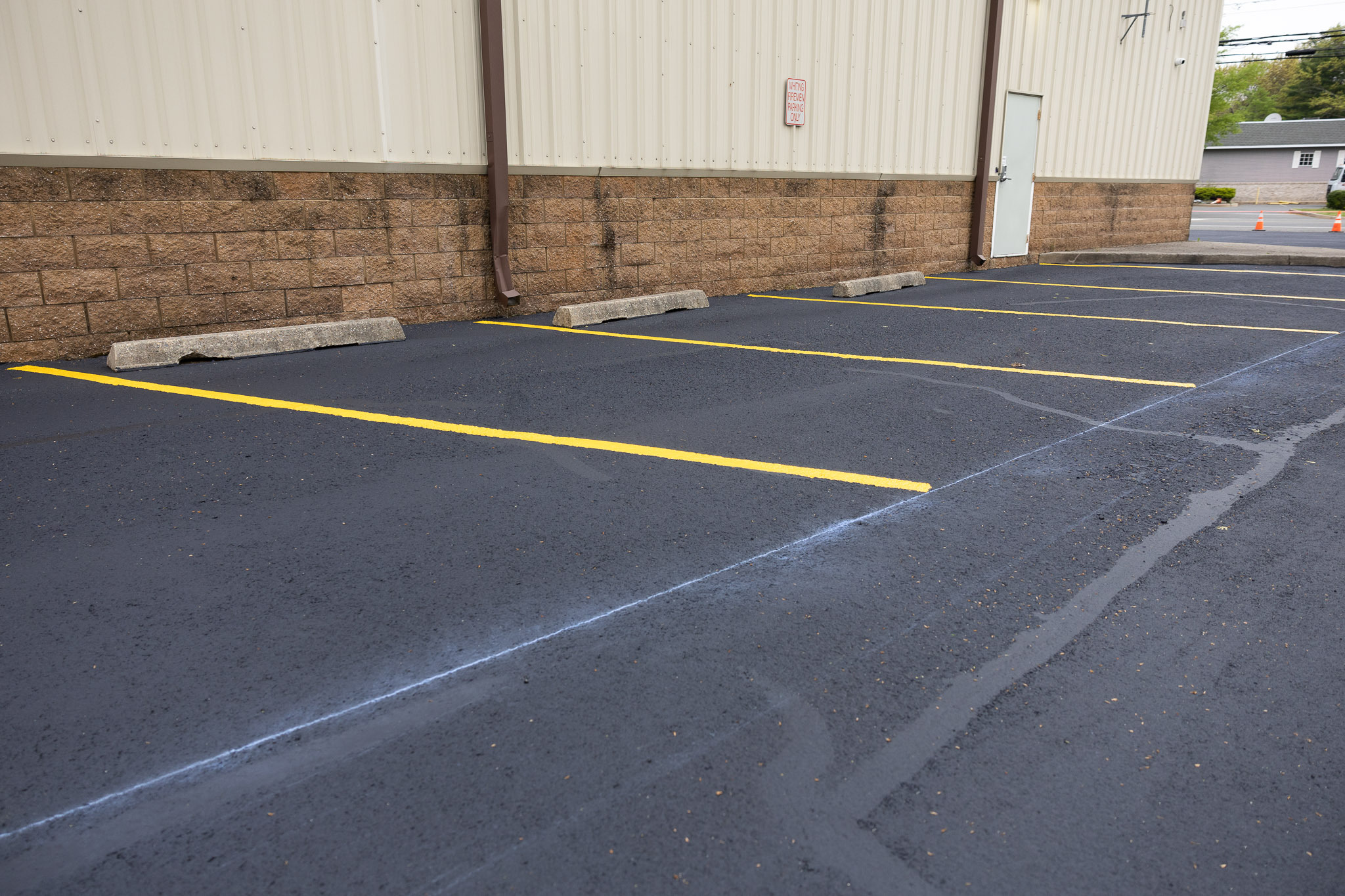 Parking lot lines and spaces side by side behind industrial building