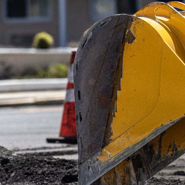 Construction machinery digging up asphalt outside apartment building