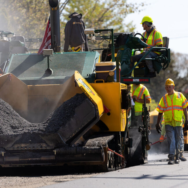 Contractors using machine to lay fresh asphalt