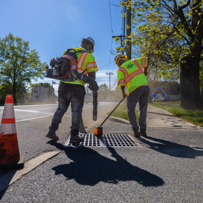Parking lot contractors cleaning grid on storm drain