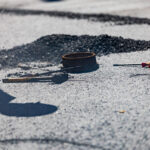 Asphalt repair tools lying on top of damaged pavement