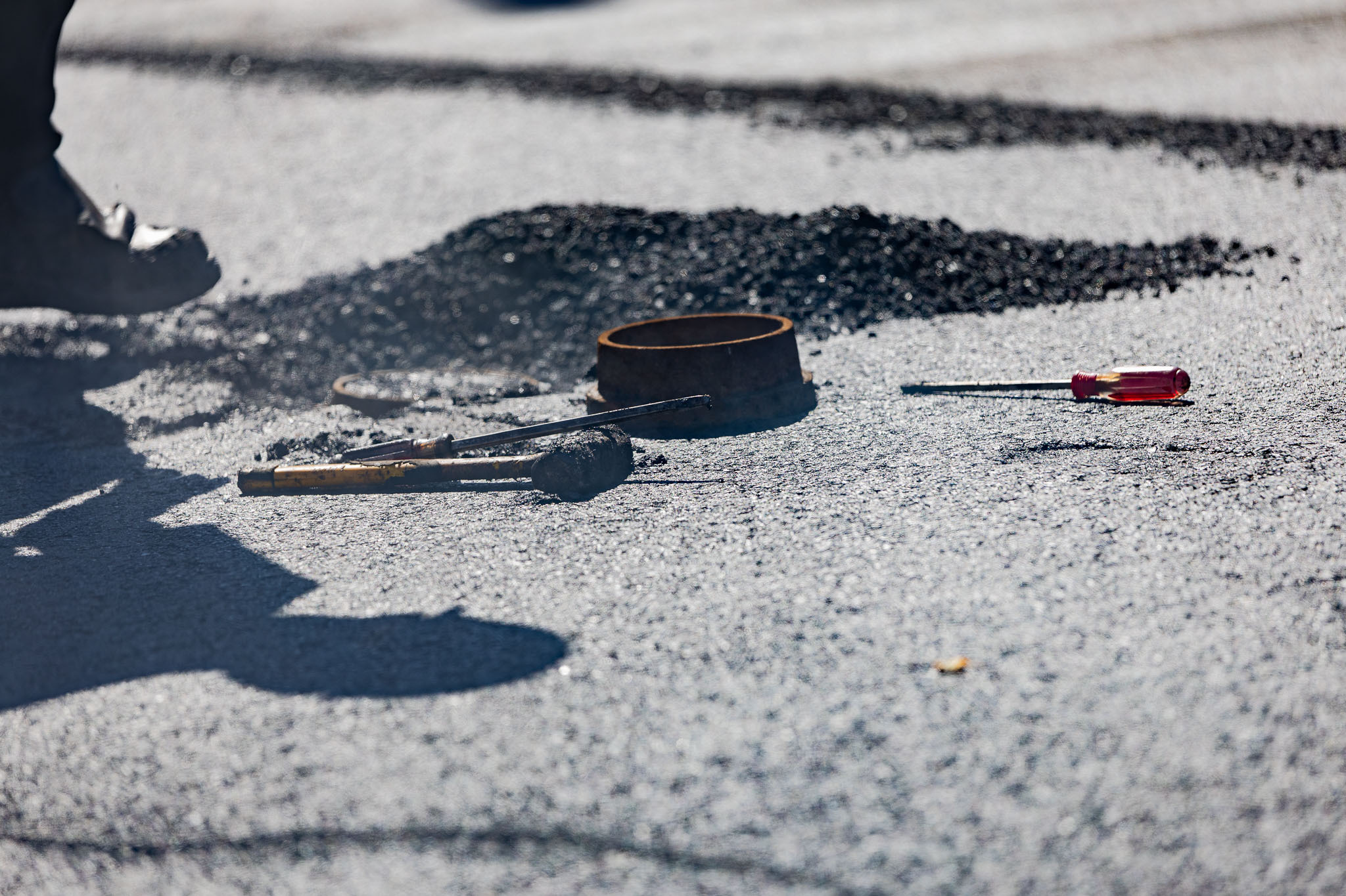 Asphalt repair tools lying on top of damaged pavement