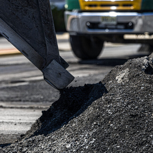 Close image of excavator scooping asphalt