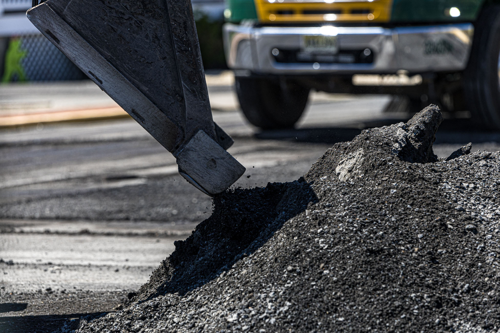 Close image of excavator scooping asphalt