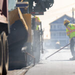 Worker and machinery performing road repairs