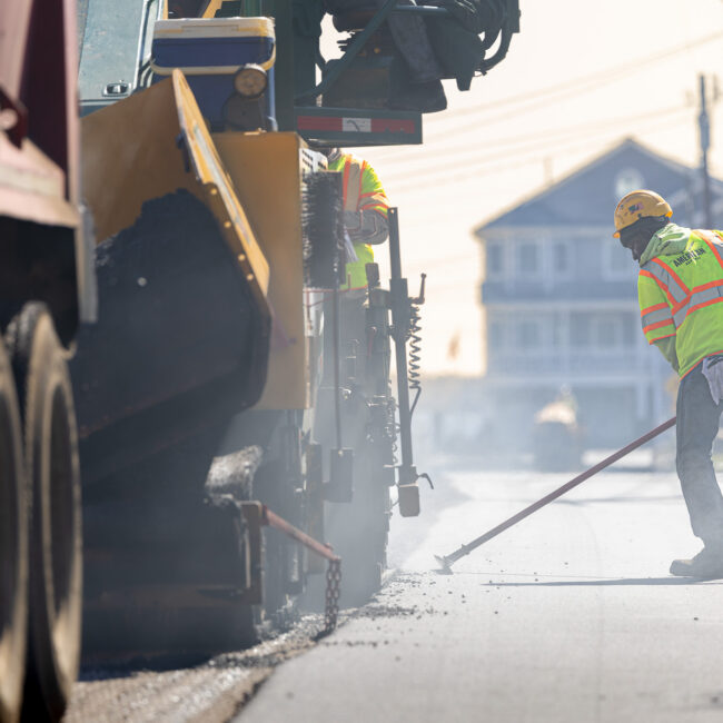 Worker and machinery performing road repairs