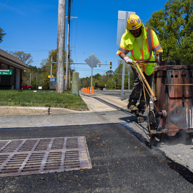 Contractor laying asphalt near catch basin grate