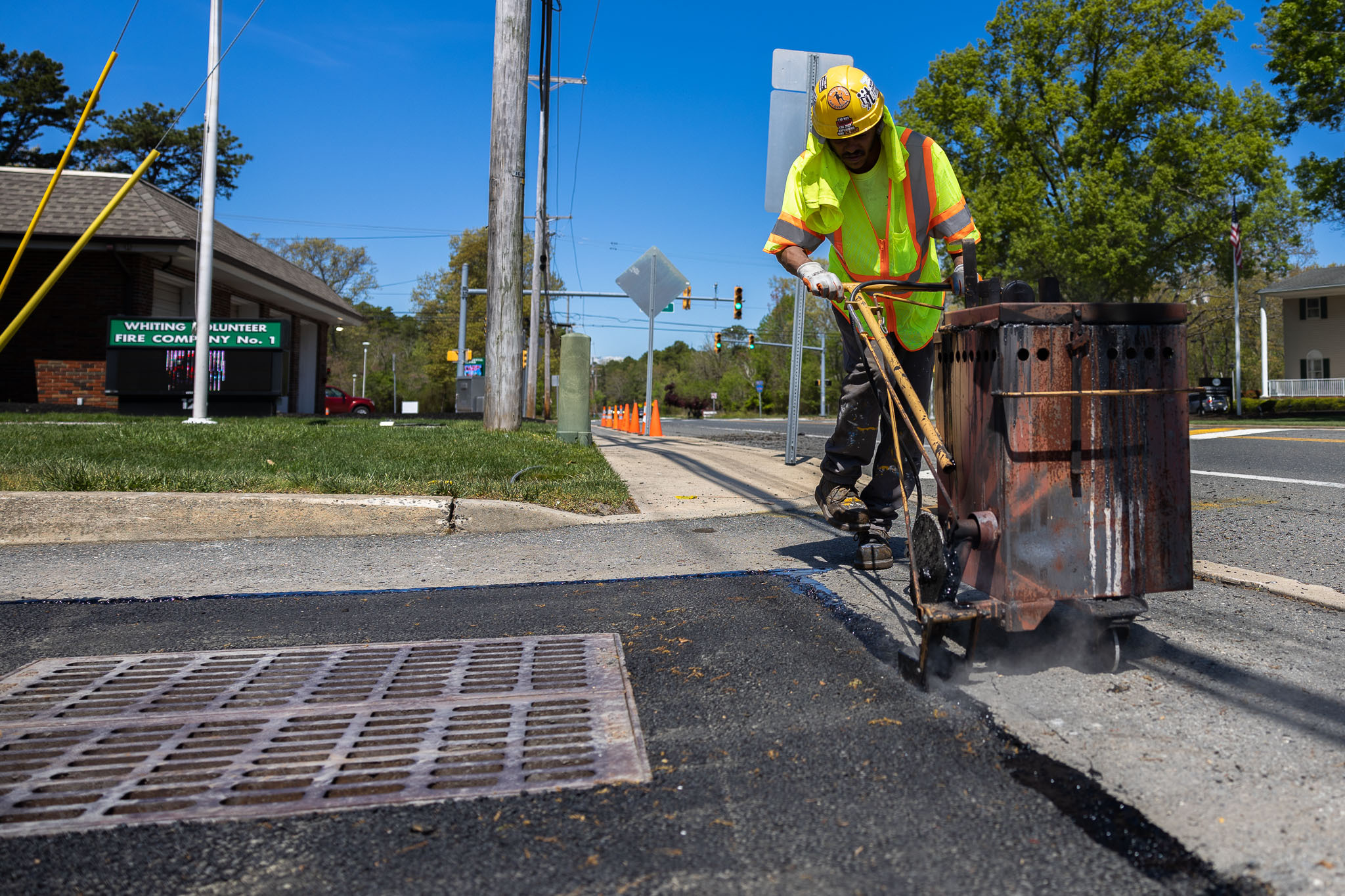 Contractor laying asphalt near catch basin grate